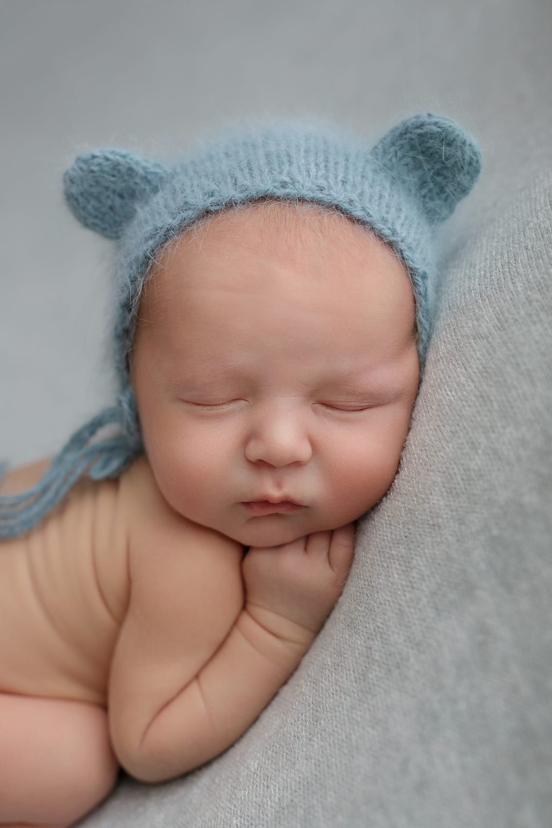 Focení miminka s modrou čepičkou na dece