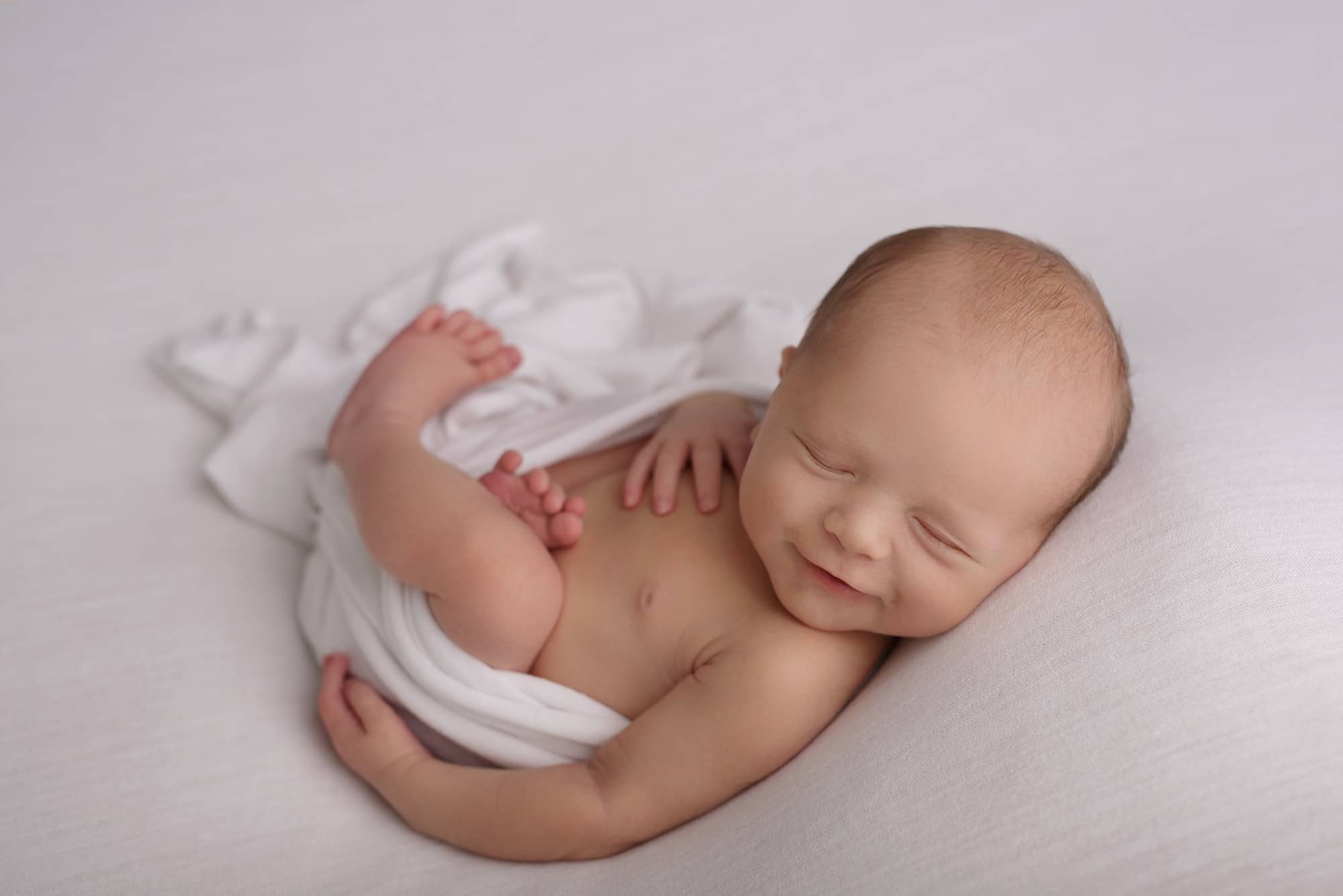 Newborn focení smějícího se miminka v bílém wrapu